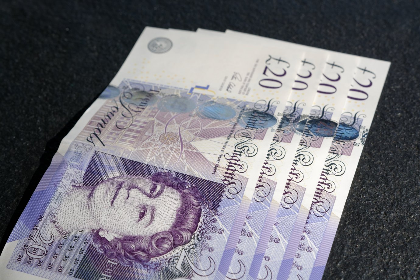 Photo by Colin Watts on Unsplash Four 20 pound notes on a black background