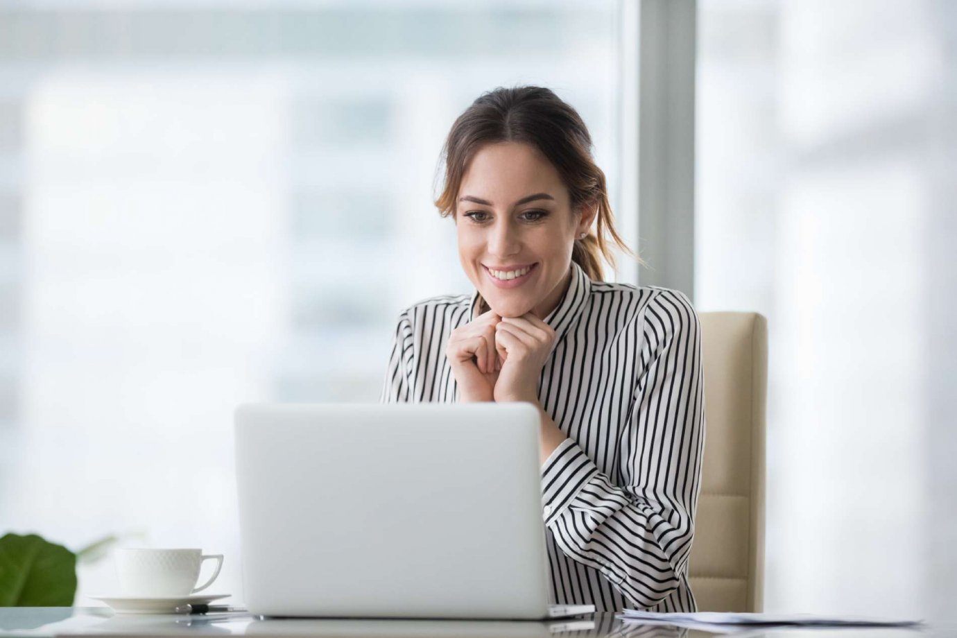 Woman Searching on Laptop A woman looking at a laptop with a happy and hopeful smile on her face.