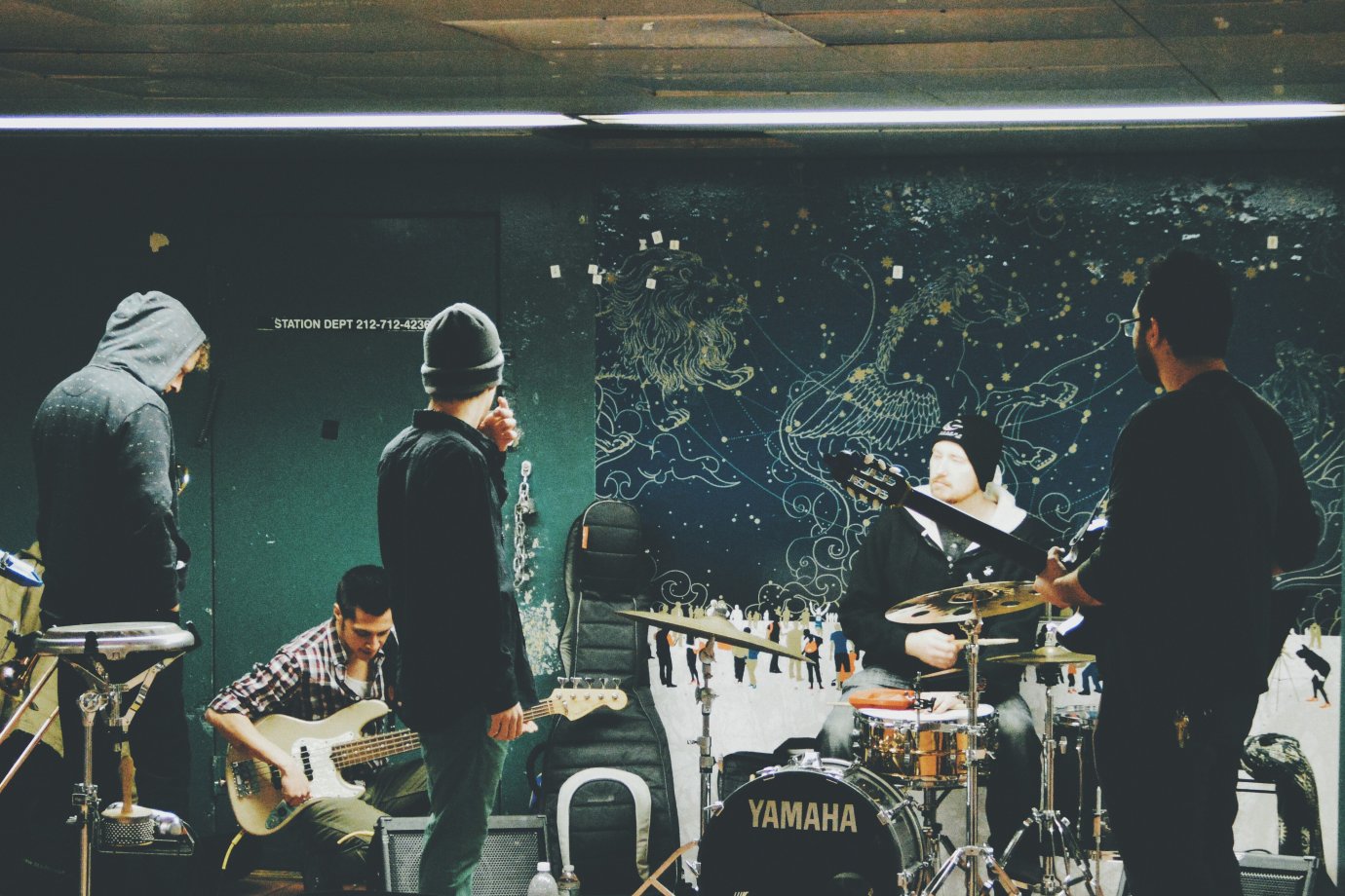 Photo by Hans Vivek on Unsplash 5 musicians rehearsing, including a drummer, guitarist, bassist, trombonist and singer.
