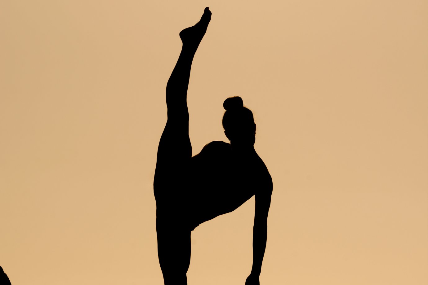 Photo by David Hofmann on Unsplash A silhouette of a person with one of their legs pointing upwards into the air.