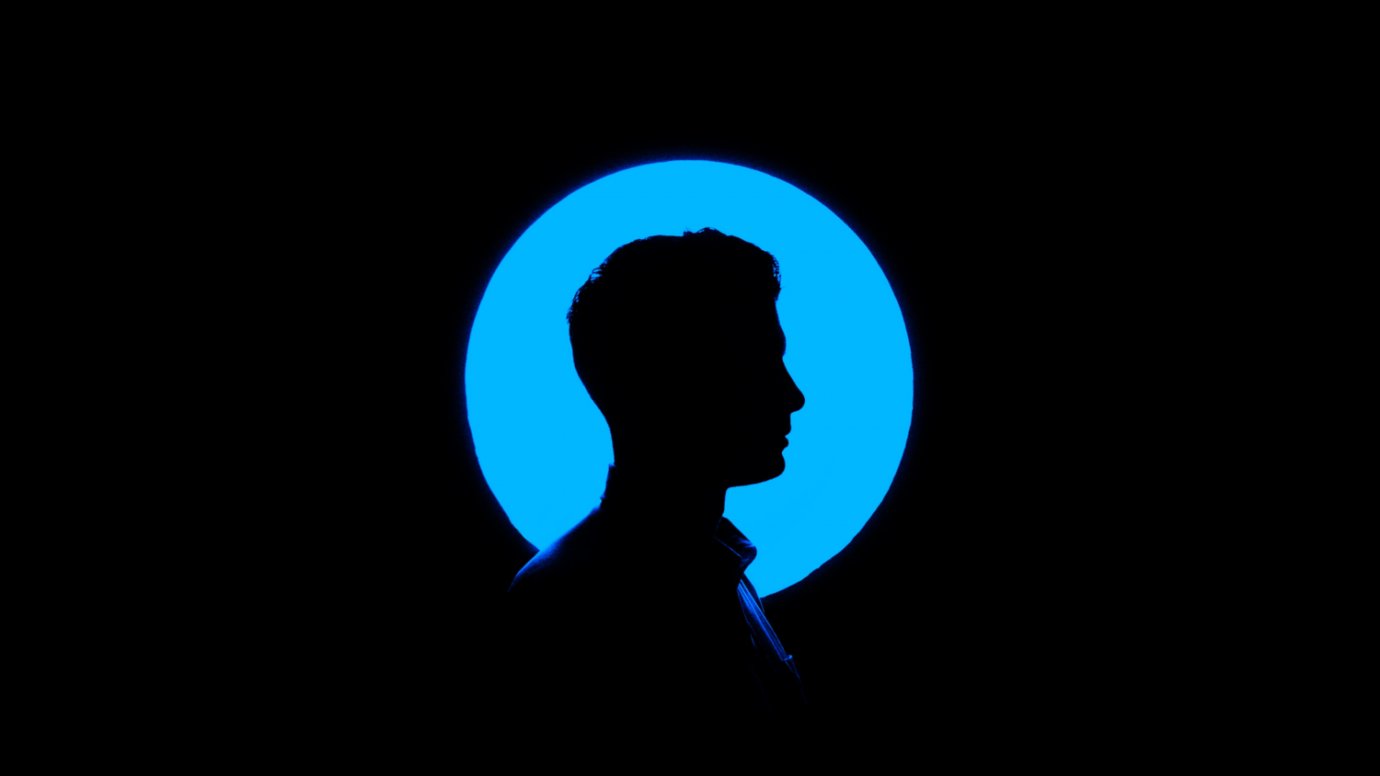 Photo by Ben Sweet on Unsplash A blue circle of light behind a silhouette of a man's profile.